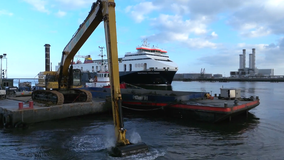 Giant long reach excavator dredging deep water at the harbor