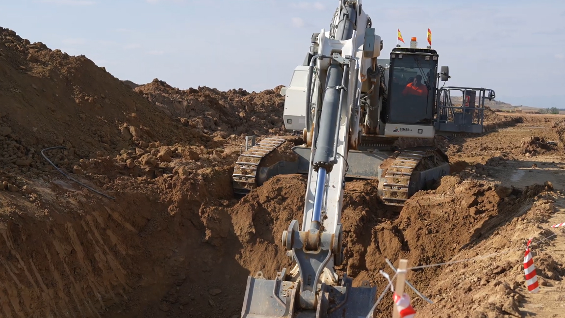 Massive excavator digs a deep trench through tough ground