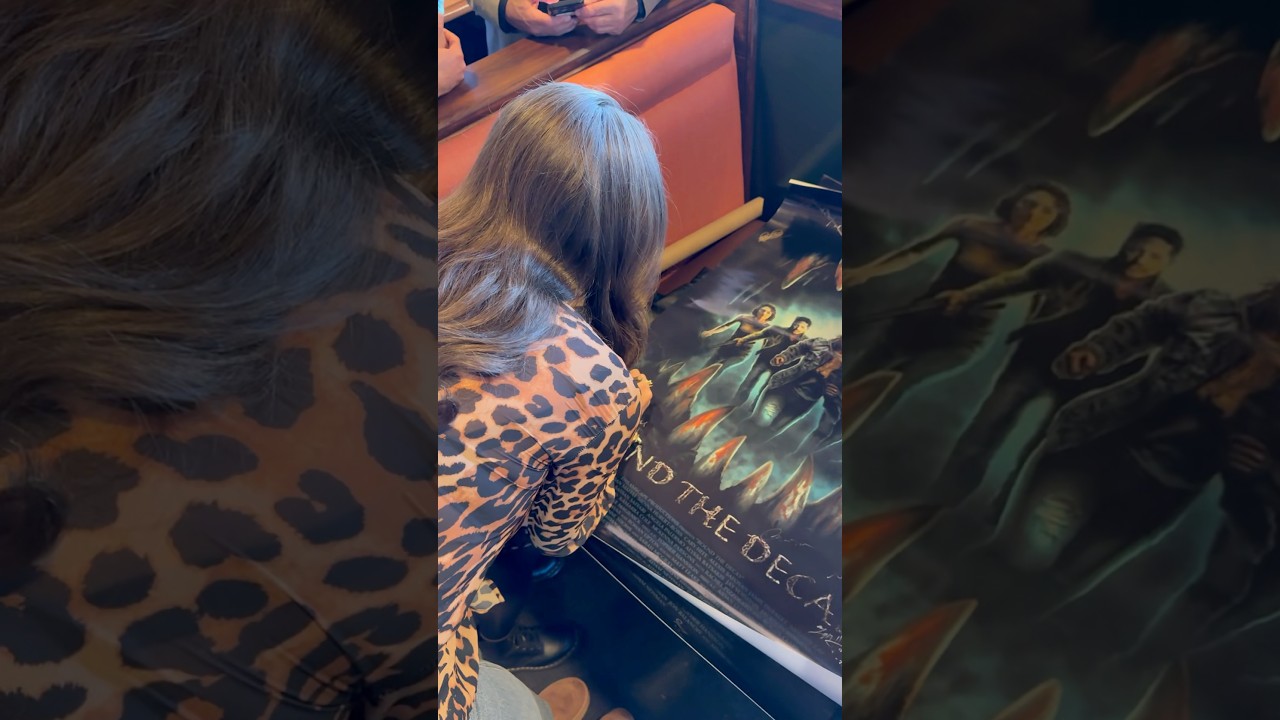 Model signs Round the Decay movie posters