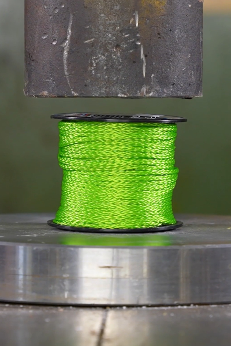 Hydraulic press crushes a green rope spool