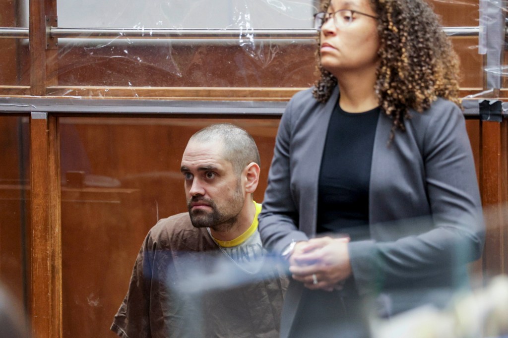 The 33-year-old (pictured with his public defender, Kimberly Greene, in February) sat partially handcuffed to a chair at the defense table beside his public defender, Kimberly Greene. Getty Images