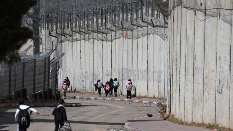 Des écoliers palestiniens le long de la barrière de séparation israélienne, dans la banlieue de Dahiat al-Barid, à Jérusalem-Est, le 24 février 2026.