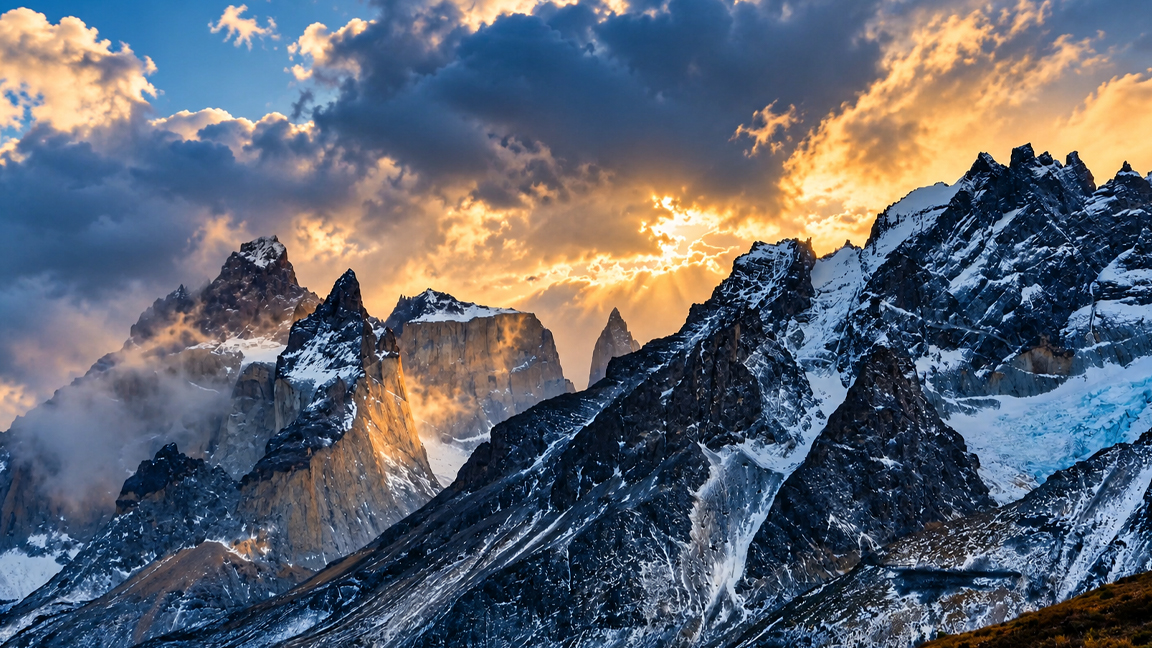 Sunlight Breaks Through Storm Clouds Above Snowy Mountain Peaks