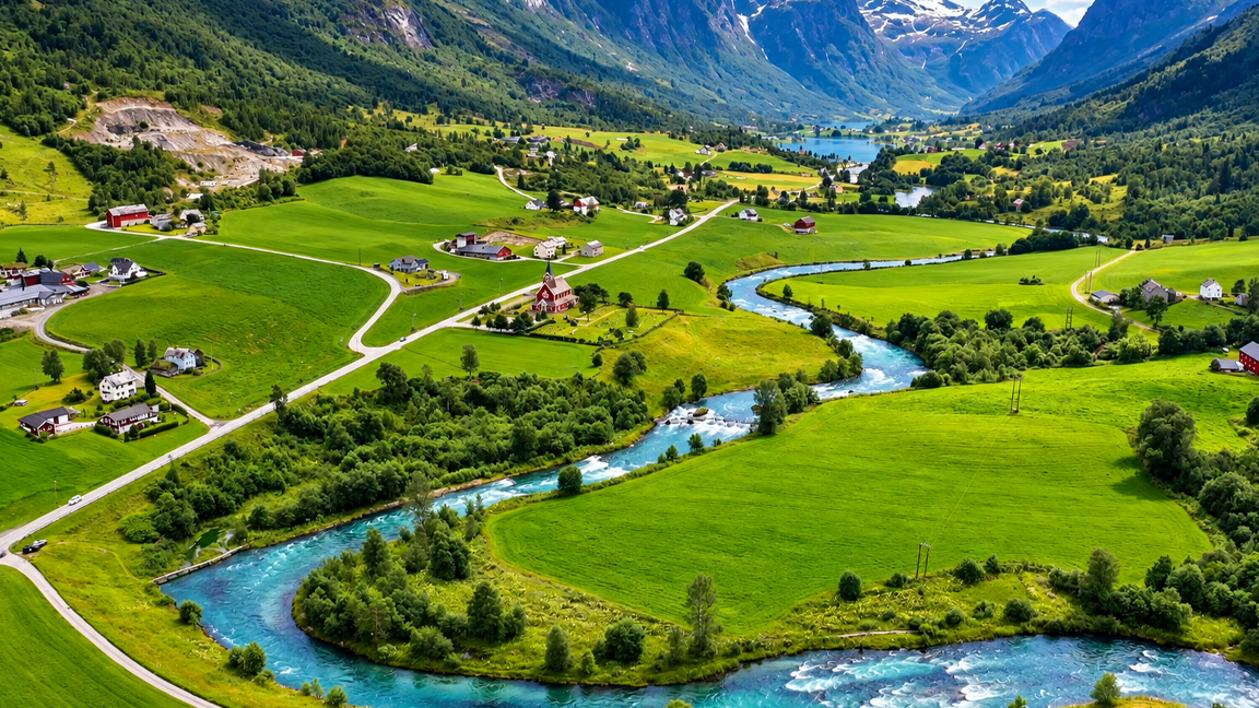 Green farmland surrounds a winding river beneath the mountains