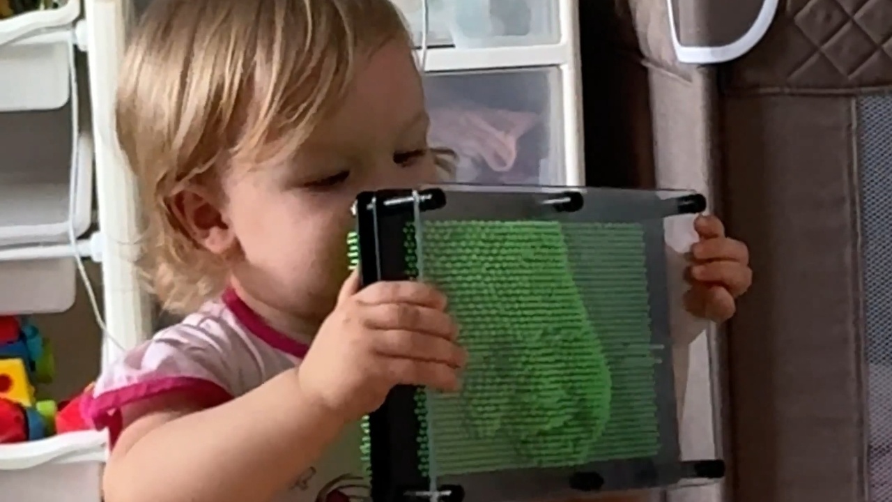 Young girl creates face impression on classic 3D pin board