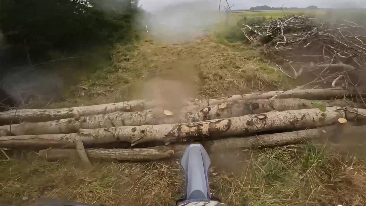 Teen rider falls while crossing log obstacle on dirt bike
