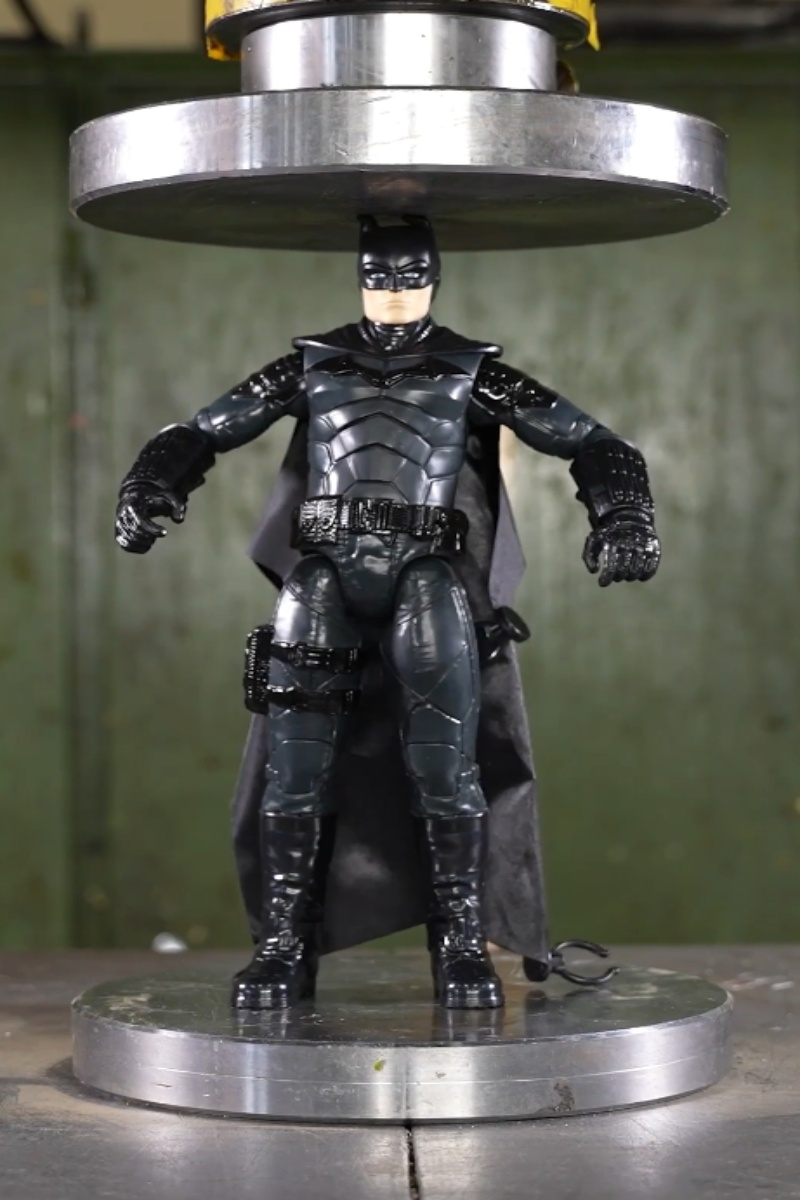 Batman action figure under a hydraulic press