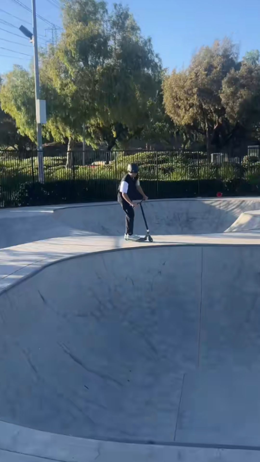 Scooter rider shows off a low riding skatepark move