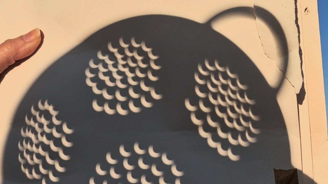 Woman uses colander to view eclipse in London