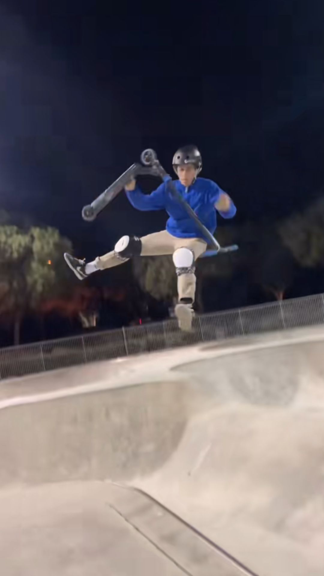 Freestyle scooter bowl riding during a night skatepark session