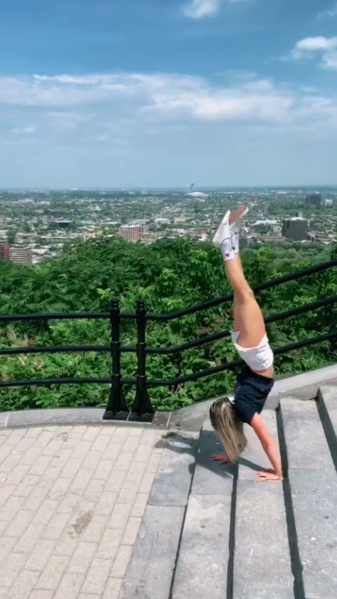 Outdoor handstand on stone steps with a city view