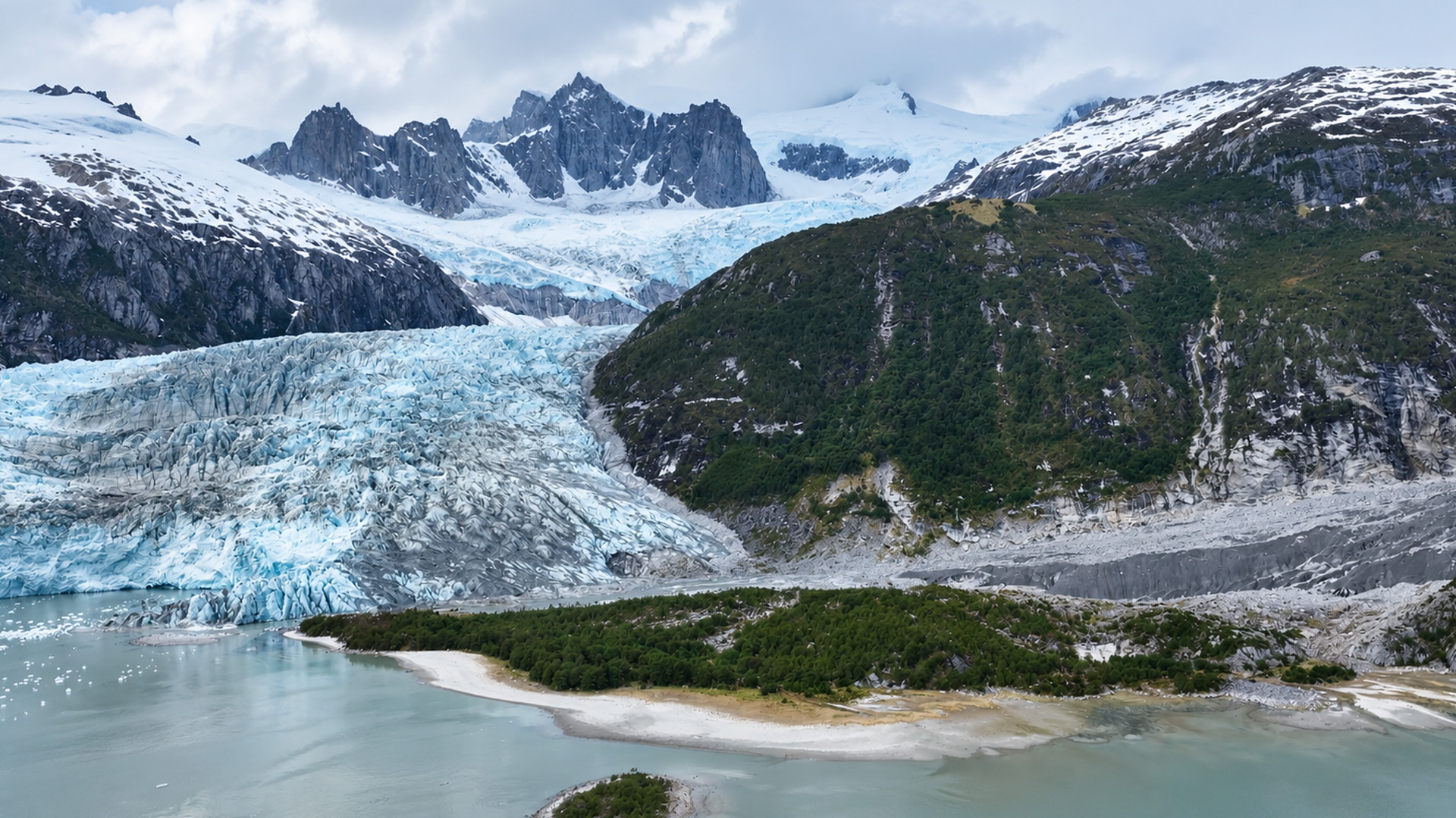 A glacier cutting through green mountain slopes