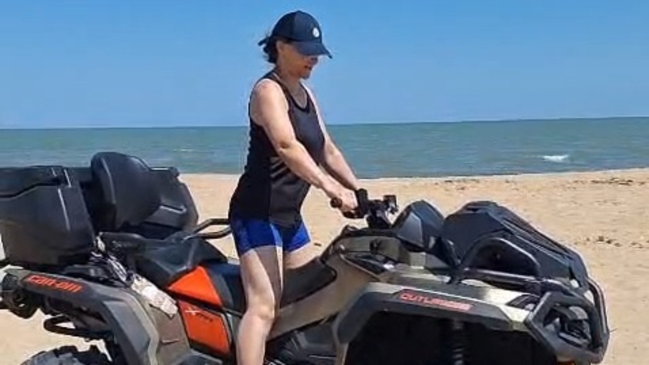 Girl loses control and falls off quad bike on beach sand