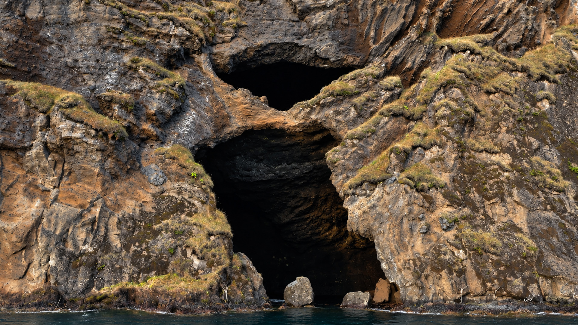 Sea caves beneath a rugged Icelandic rock wall