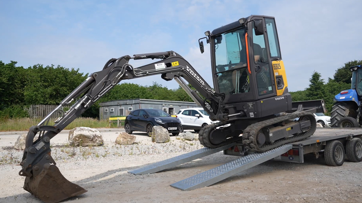 Skilled operator unloading a mini excavator with precision