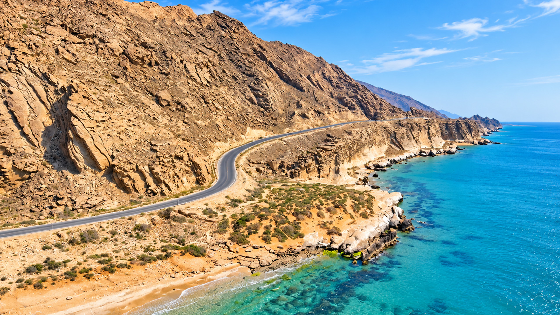 A winding coastal road between mountains and blue sea
