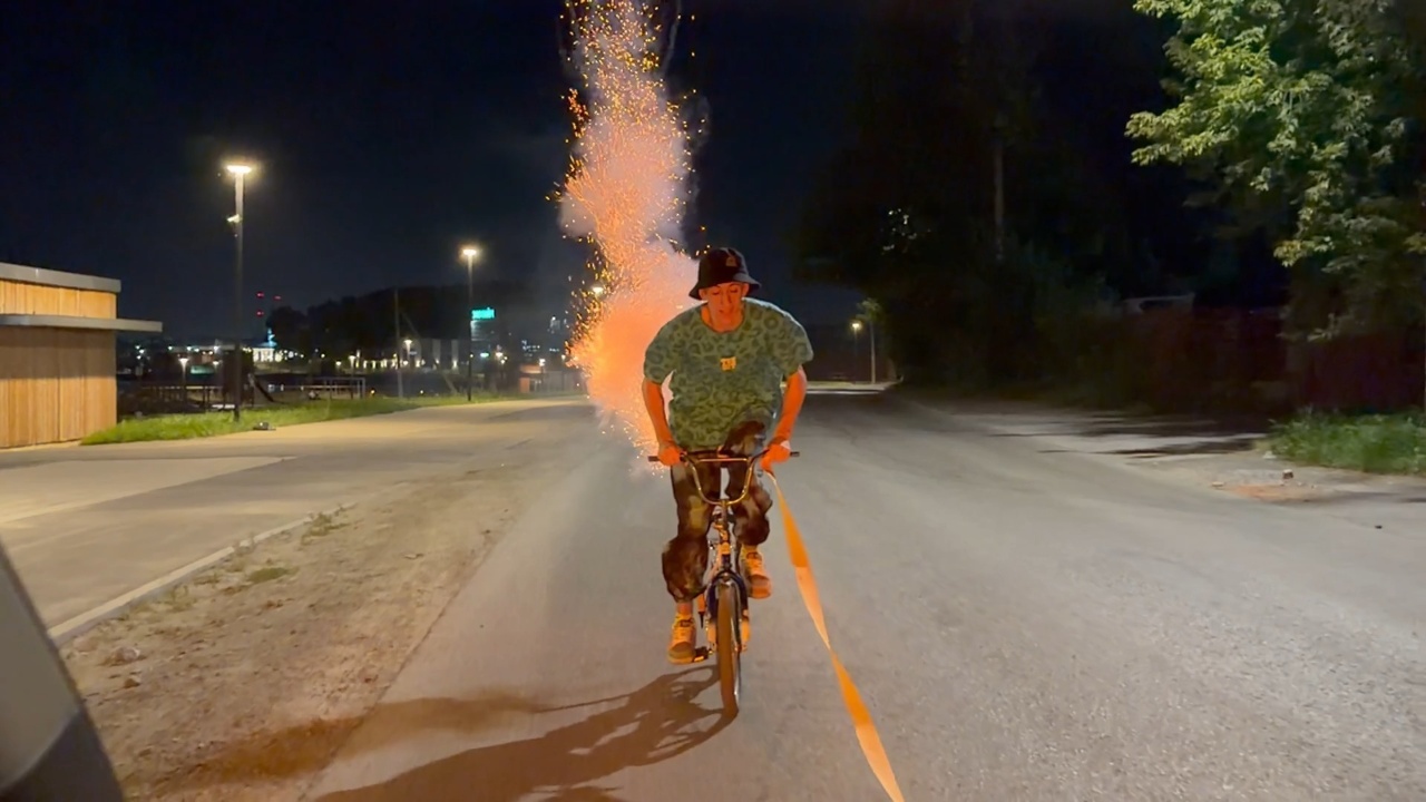 Man gets towed on cycle while Roman candles fire sparks at him