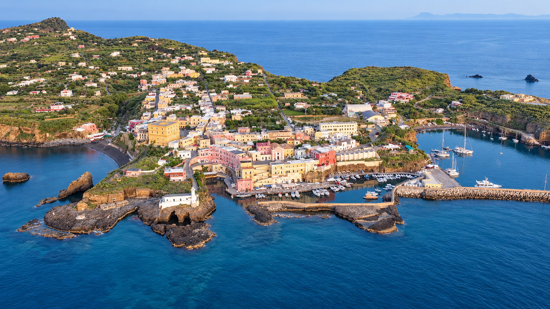 Pastel buildings rise above Ventotene’s rocky shore