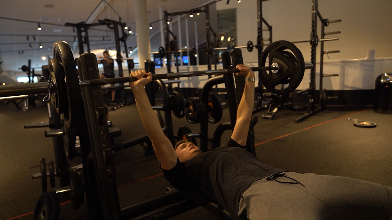 Performing barbell bench press to build upper body strength