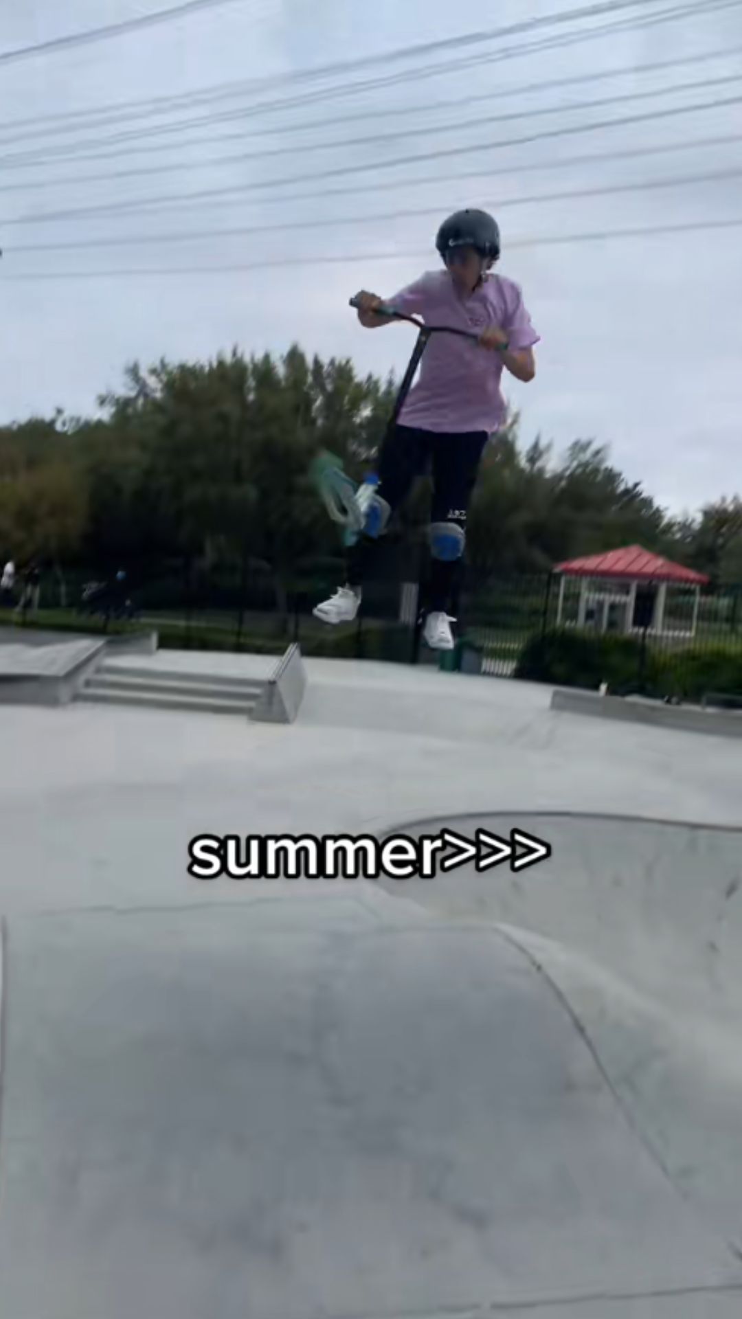 Scooter rider carves along a concrete skatepark ramp