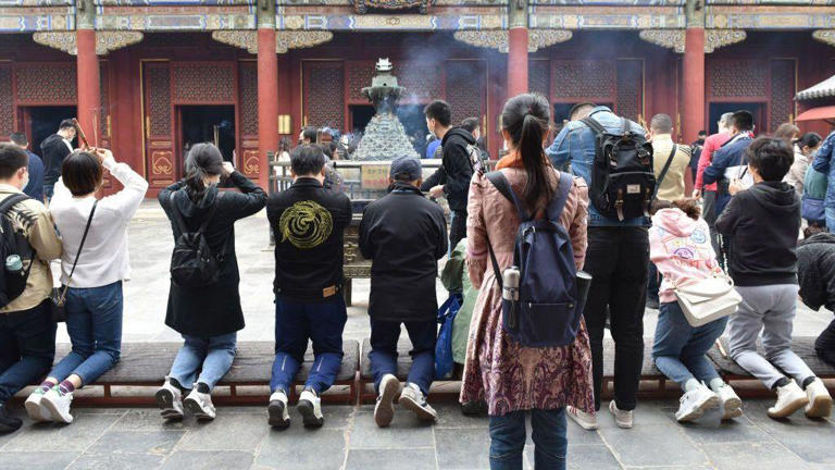 Jóvenes rezando en un templo de Pekín para pedir buenas perspectivas laborales y matrimoniales.