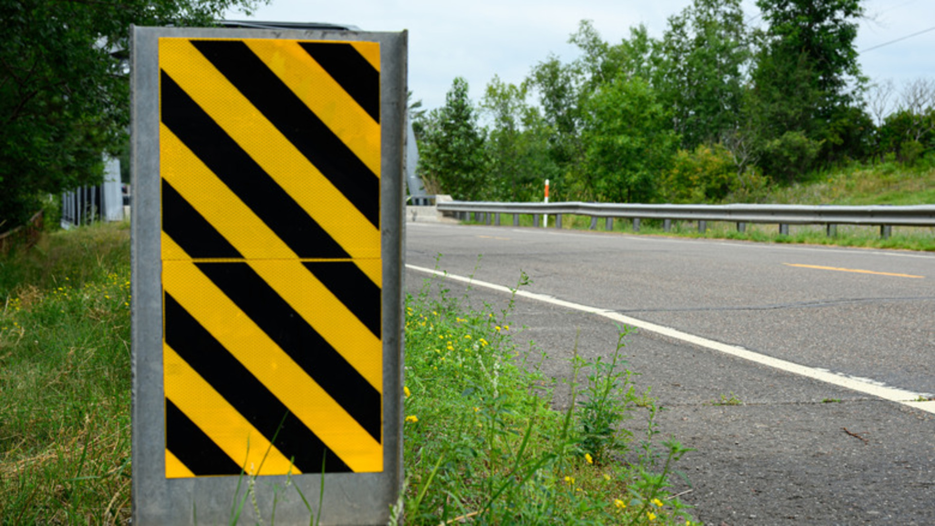 What does a diagonal yellow and black striped road sign mean?