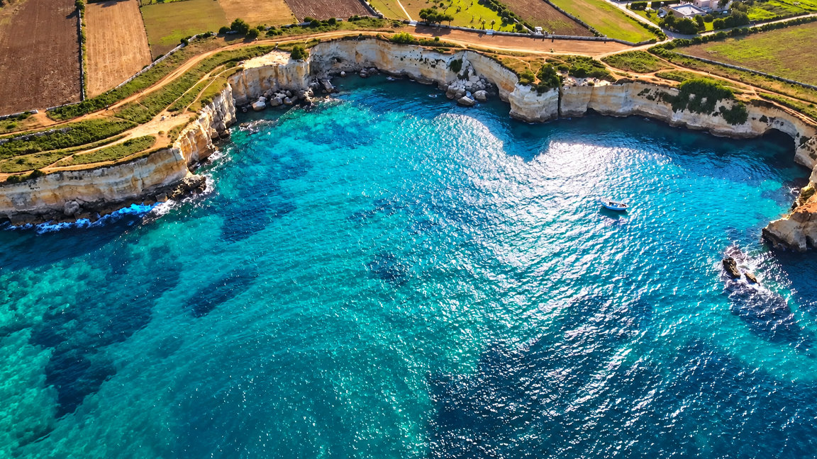 Hidden turquoise cove beneath towering coastal cliffs