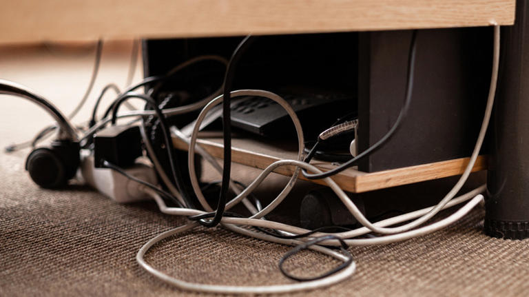 Tangled cables underneath a desk