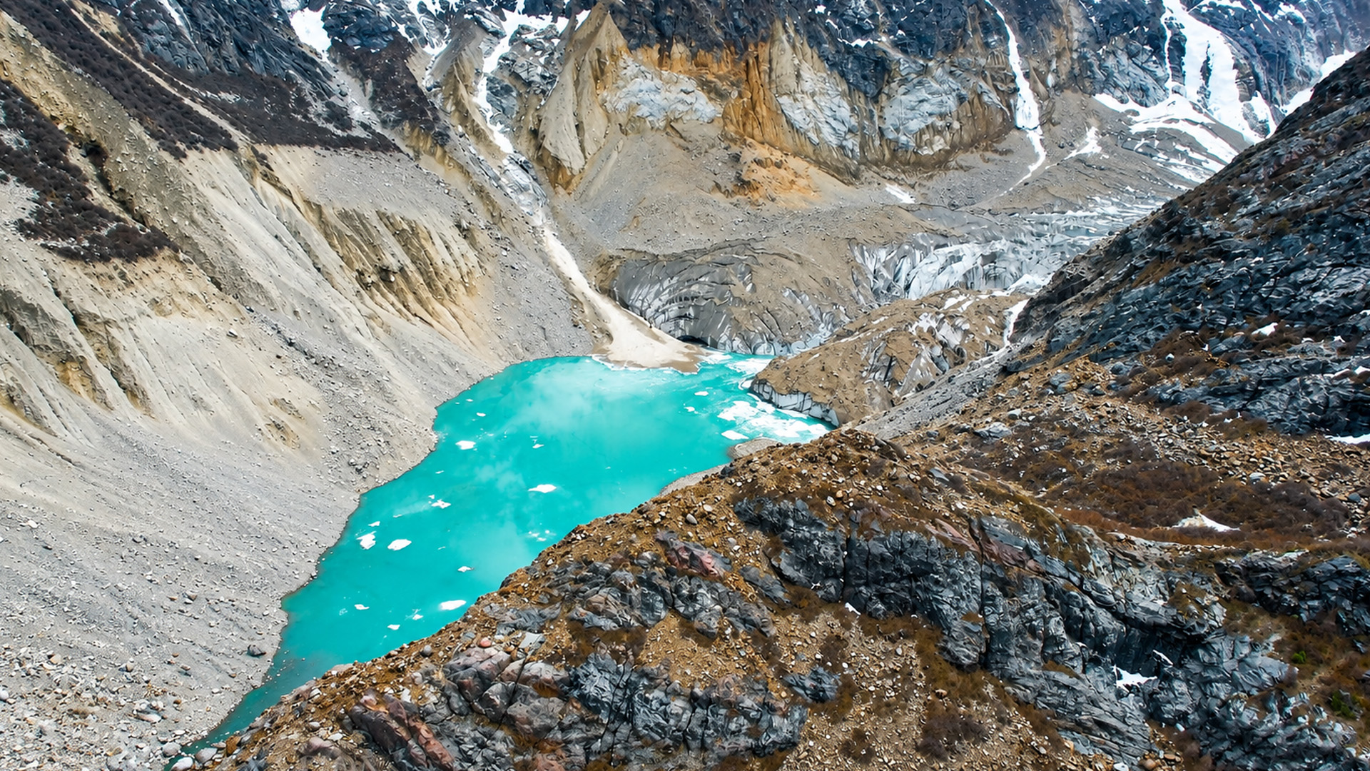 Turquoise water between ice and barren mountain slopes