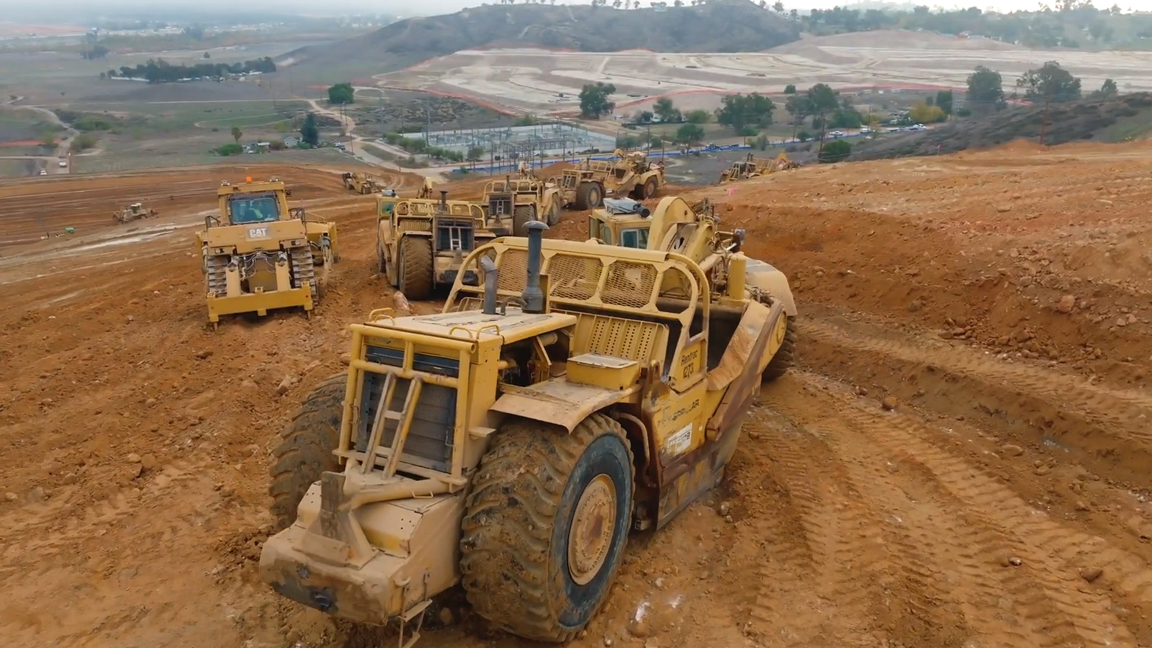 Massive earthmoving machines working together on a giant construction site