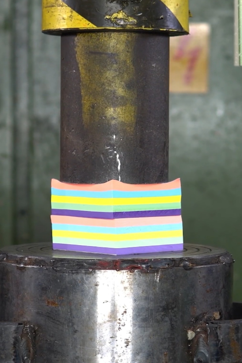 Hydraulic press crushes colorful paper stack