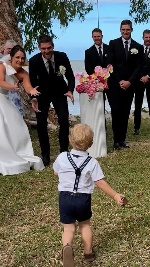 Young ring bearer throws ring box like a rugby ball at wedding