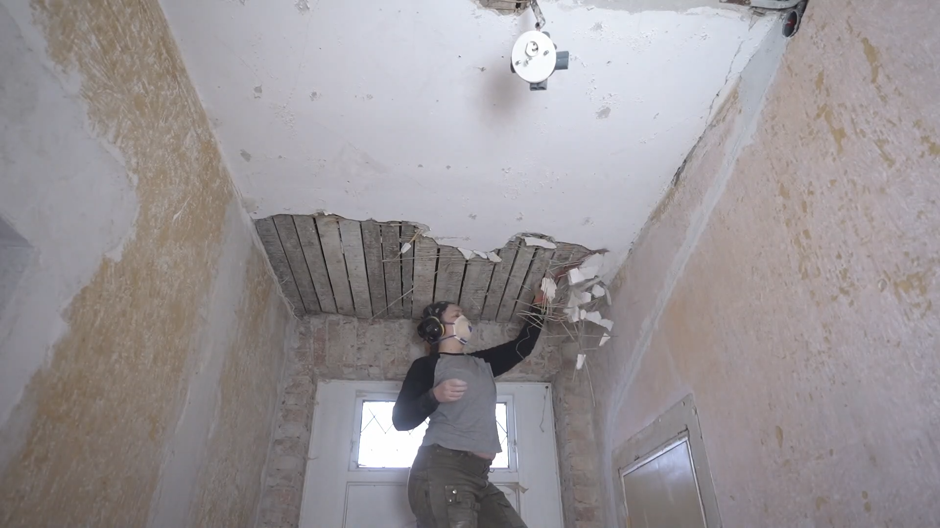 Removing damaged lime plaster from a historic hallway ceiling
