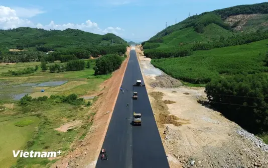Nhà thầu thi công thảm bêtông nhựa nền đường một tuyến cao tốc. (Ảnh: Khánh Hùng/Vietnam+)