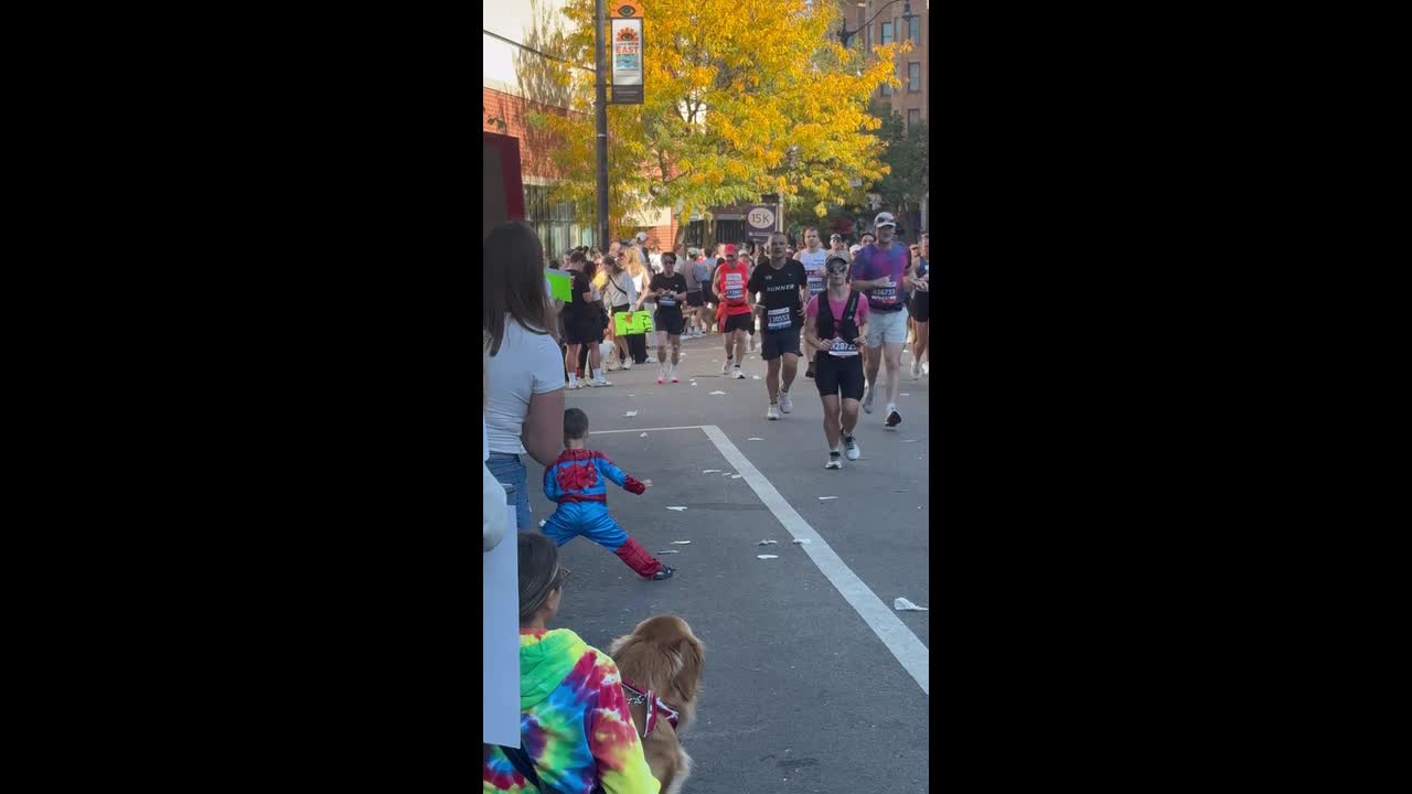 Little boy dressed as Spider-Man high fives runners during Chicago Marathon