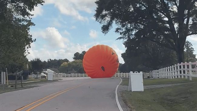 Giant inflatable pumpkin rolls down road, menaces cars