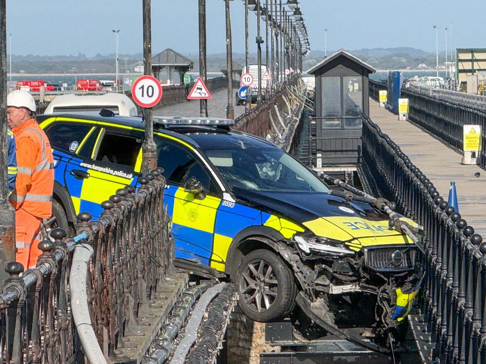 Police car dangling precariously off seaside pier in crash trapping two ...