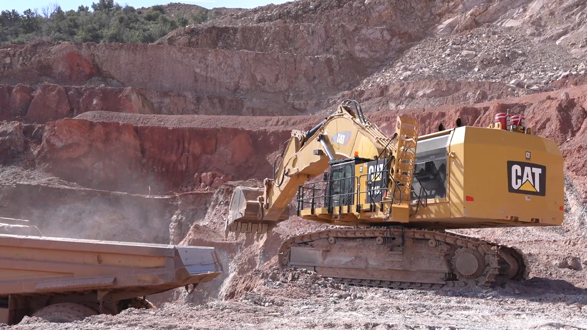 Massive mining excavator loading giant dump truck in extreme quarry ...