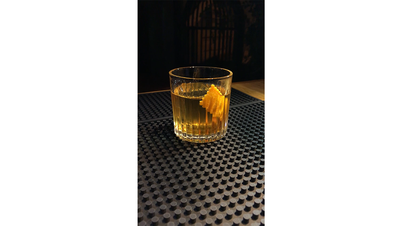 Crafting golden amber cocktail with orange peel, creating elegant ...