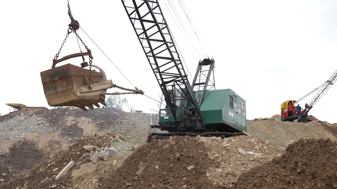 Giant dragline crane with enormous bucket moving tons of earth and rocks