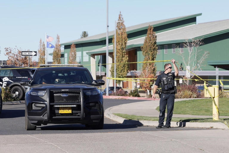 Rob Kerr/Reuters - FOTO: Un trabajador de emergencias sostiene la cinta policial en el lugar de un tiroteo en la escuela primaria Silver Rail en Bend, Oregón, el 15 de octubre de 2026.