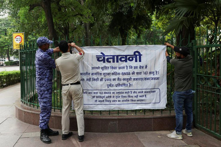 Security officers hang a poster with a public warning ahead of the flag rally announced by the Cockroach Janta Party (CJP) seeking the resignation of India's Chief Election Commissioner Gyanesh Kumar, in New Delhi, India, October 16, 2026. REUTERS/Bhawika Chhabra