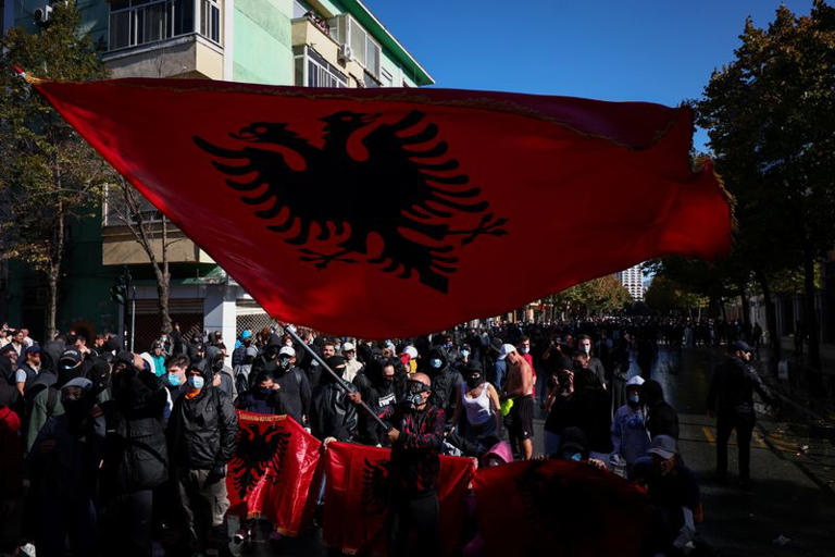 A demonstrator wearing a gas mask waves a large Albanian flag during an anti-government protest by students in Tirana, Albania, October 16, 2026. REUTERS/Florion Goga