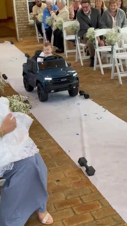 Sleeping ring bearer rides down aisle in remote-controlled car