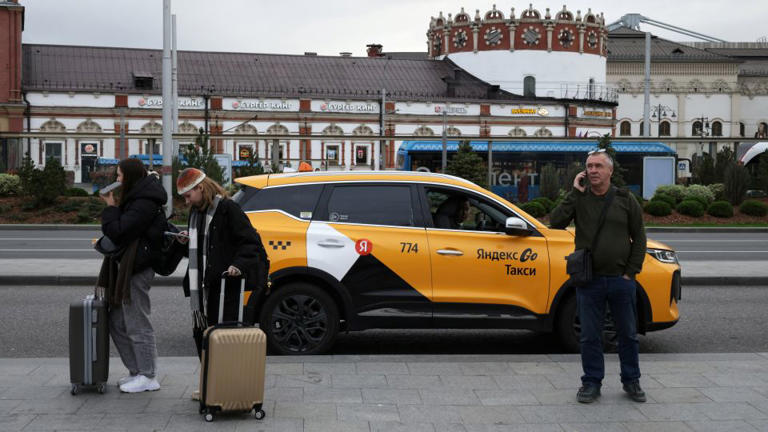 People stand next to a Yandex Taxi car on a street in Moscow, Russia, October 11, 2026. - Anastasia Barashkova/Reuters