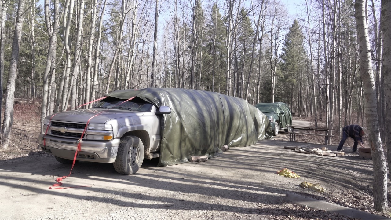 They covered 2 SUVs with one giant tarp then spent the night inside ...