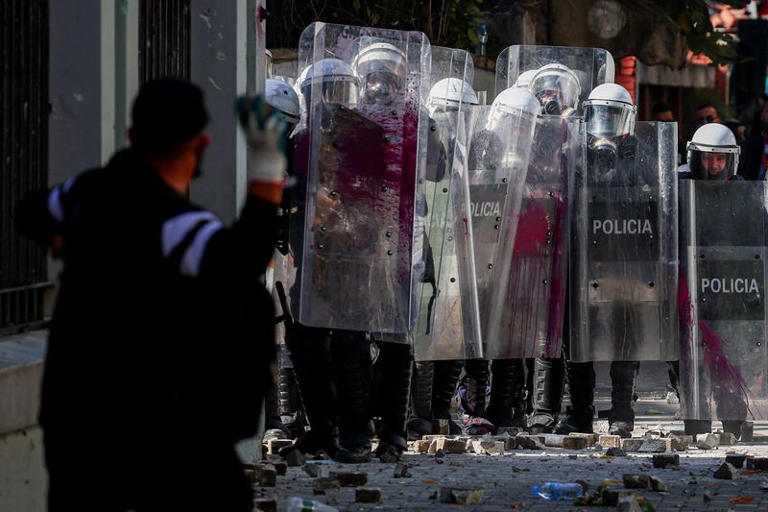 A protester swings to hurl an object, at riot police officers holding a line, amid an anti-government protest by students in Tirana, Albania, October 17, 2026. REUTERS/Florion Goga