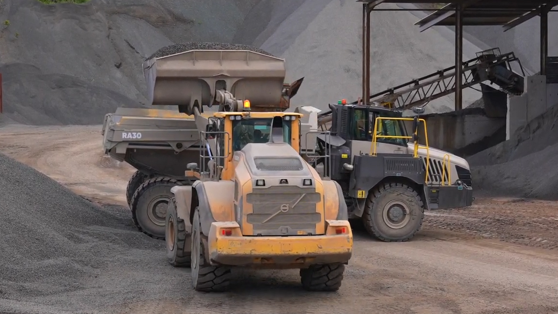 Giant dump truck and wheel loader in action at busy aggregate quarry