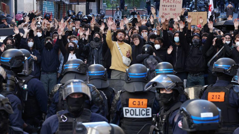 Masked protesters raise their arms as they face off with French riot police during a demonstration in a street near the Gare du Nord train station in Paris on Saturday, October 17, 2026. - Abdul Saboor/Reuters