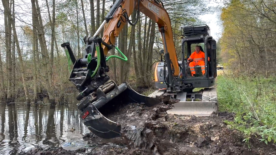 Excavator tiltrotator skills cleaning a waterlogged forest ditch